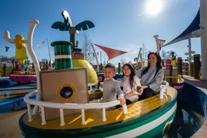 Niños y padres disfrutan del paseo Mr. Bull's High Striker en Peppa Pig Theme Park en Dallas Fort Worth. Las familias emocionadas son elevadas hacia arriba y hacia abajo en este divertido paseo, experimentando la diversión y emoción de esta atracción interactiva.