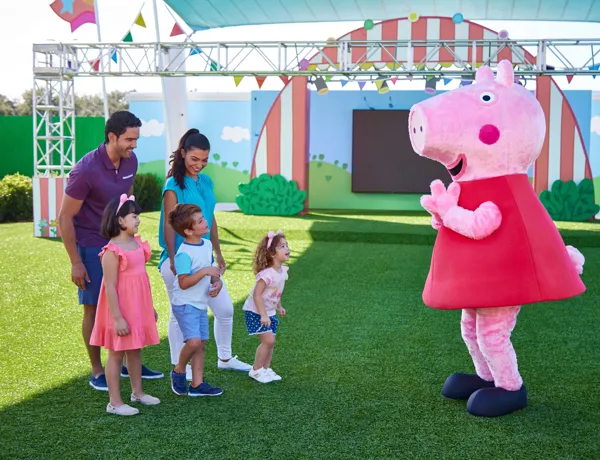 A family meets Peppa Pig at the Showtime Arena in Peppa Pig Theme Park, Dallas Fort Worth. The children excitedly pose for a photo with their favorite characters, creating memorable moments in the fun-filled atmosphere of the park.