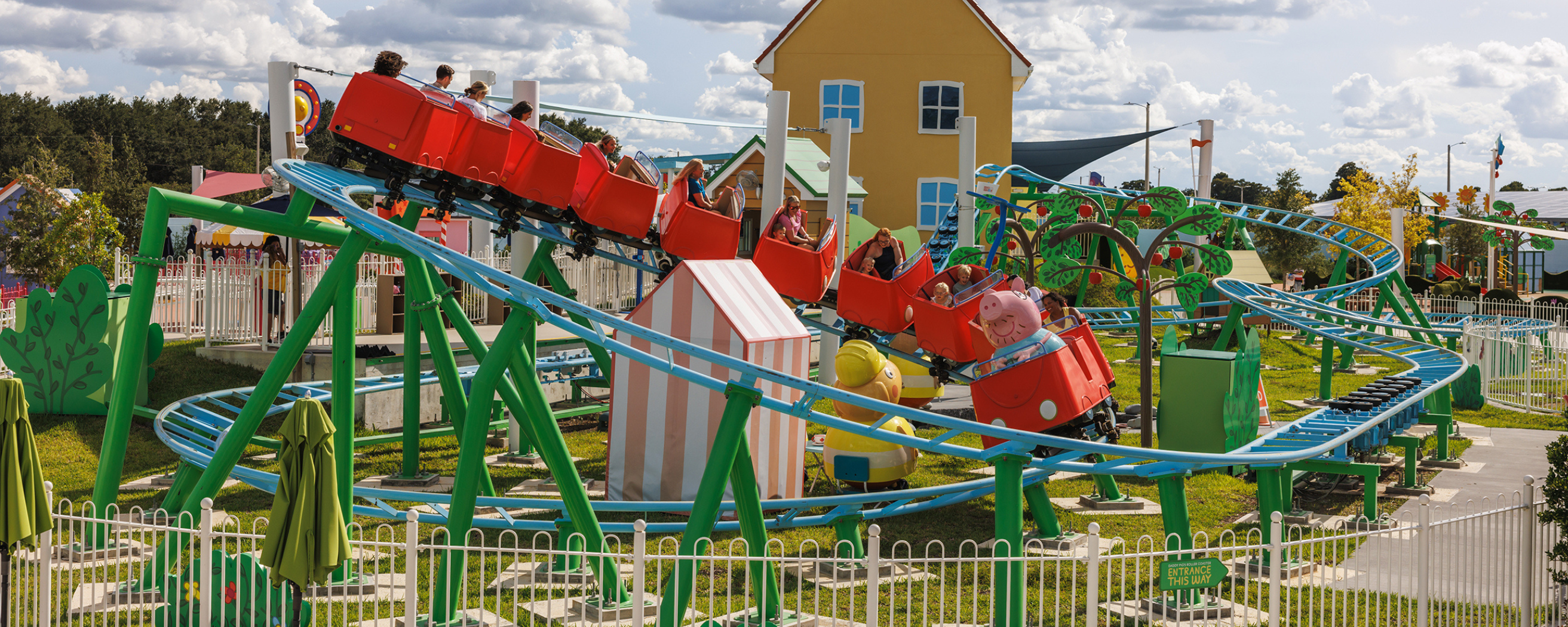 Guests enjoying a colorful roller coaster ride at Peppa Pig Theme Park in Florida